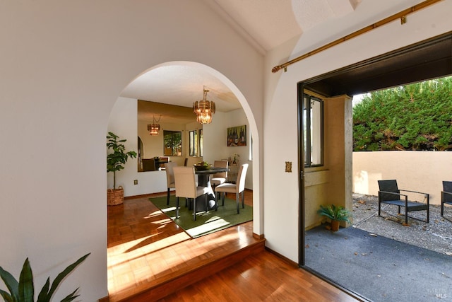 interior space with lofted ceiling, arched walkways, parquet flooring, and an inviting chandelier