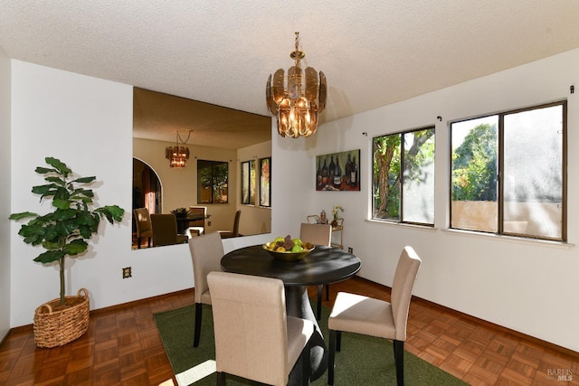 dining space featuring a chandelier, a textured ceiling, and baseboards