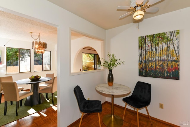 dining space featuring a healthy amount of sunlight, baseboards, a textured ceiling, and ceiling fan with notable chandelier