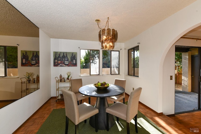 dining room featuring arched walkways, a notable chandelier, and a textured ceiling