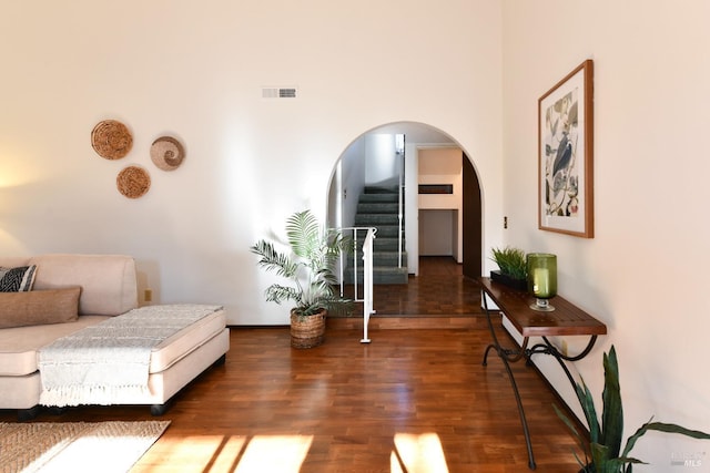 sitting room featuring arched walkways, dark wood-style flooring, stairway, and visible vents