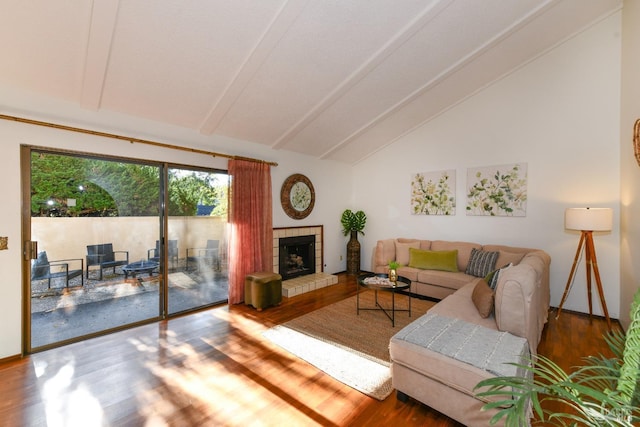 living room featuring lofted ceiling with beams, a tiled fireplace, and wood finished floors