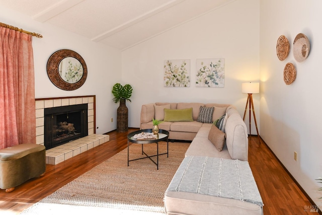 living area with lofted ceiling with beams, dark wood-style floors, and a tiled fireplace