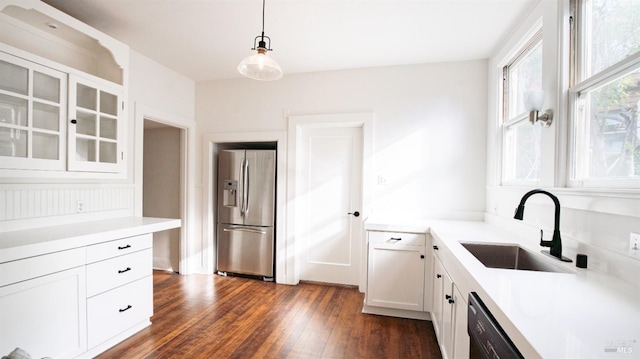 kitchen featuring stainless steel fridge, dark wood-type flooring, sink, white cabinets, and hanging light fixtures