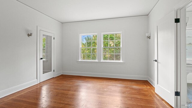 spare room featuring wood-type flooring and plenty of natural light