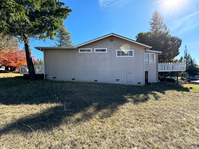 view of side of property featuring a deck and a lawn