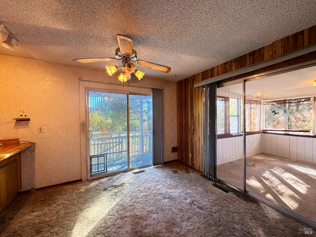 interior space featuring ceiling fan, a wealth of natural light, a textured ceiling, and carpet flooring