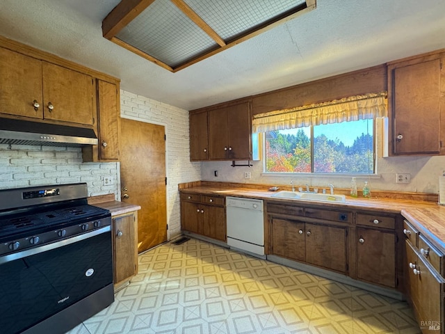 kitchen featuring gas range, sink, a textured ceiling, and white dishwasher