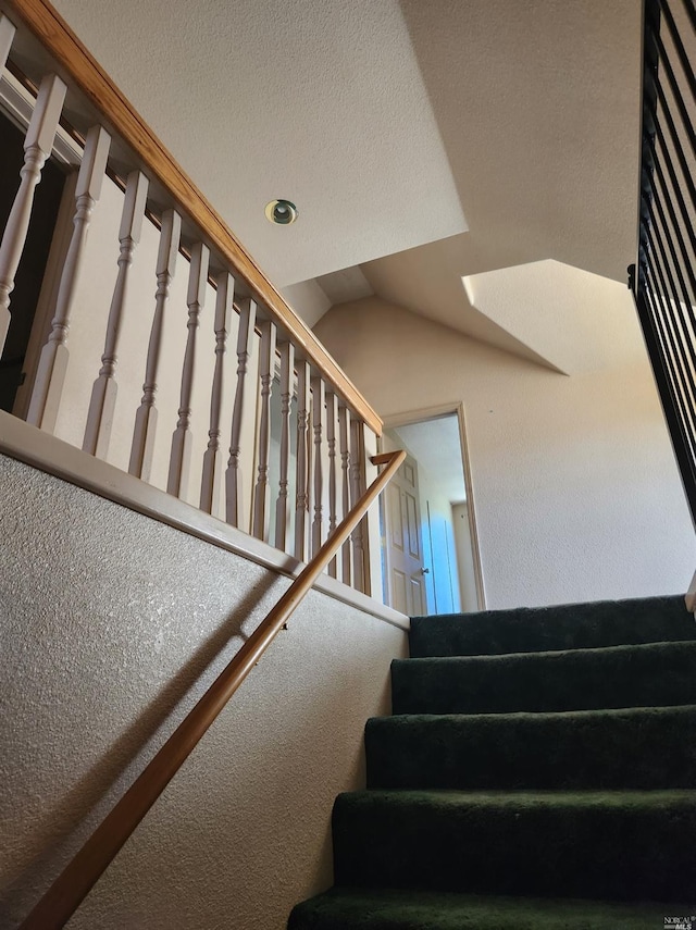 stairs with a textured ceiling and vaulted ceiling