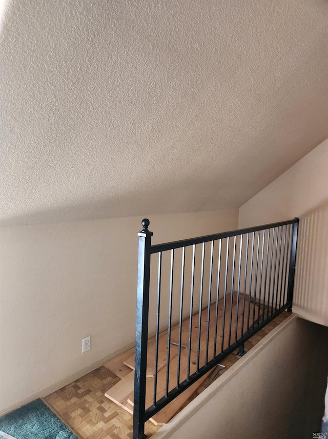 staircase featuring a textured ceiling and parquet flooring