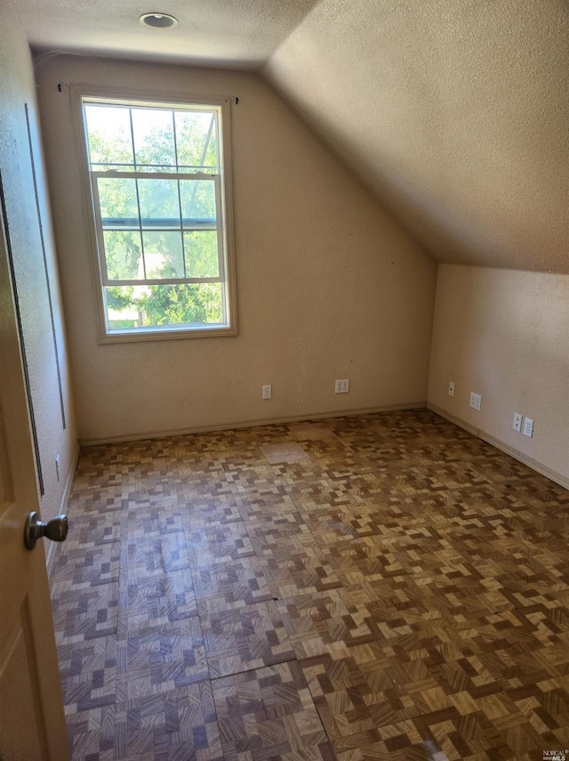 additional living space with parquet floors, a textured ceiling, and vaulted ceiling