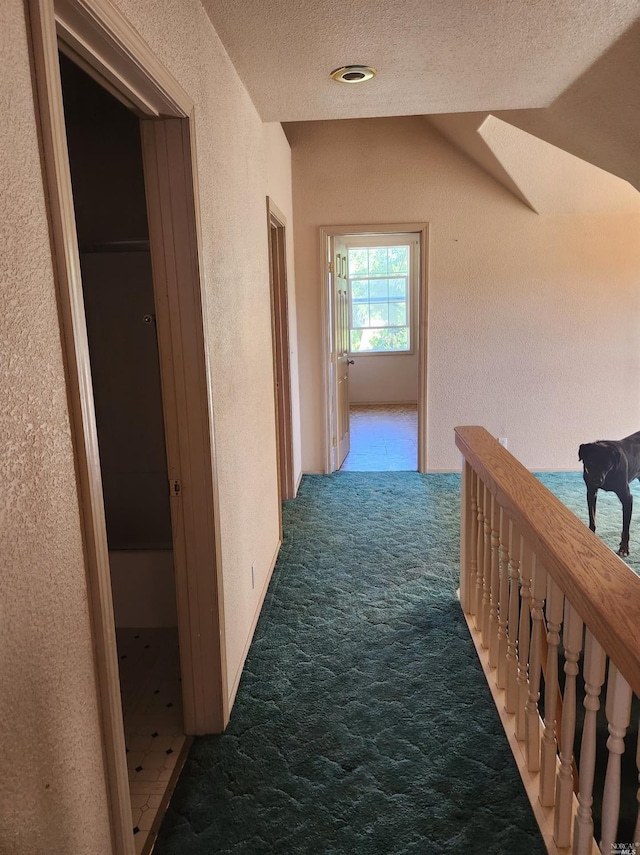 hall with a textured ceiling and carpet flooring