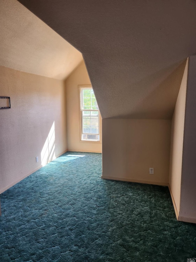 bonus room with lofted ceiling, a textured ceiling, and dark carpet