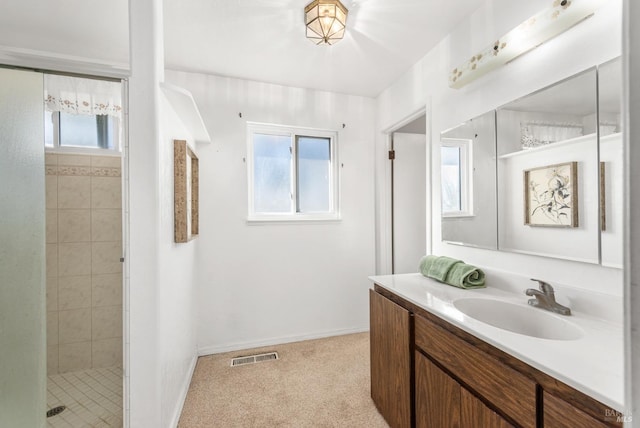 bathroom with tiled shower, a wealth of natural light, and vanity