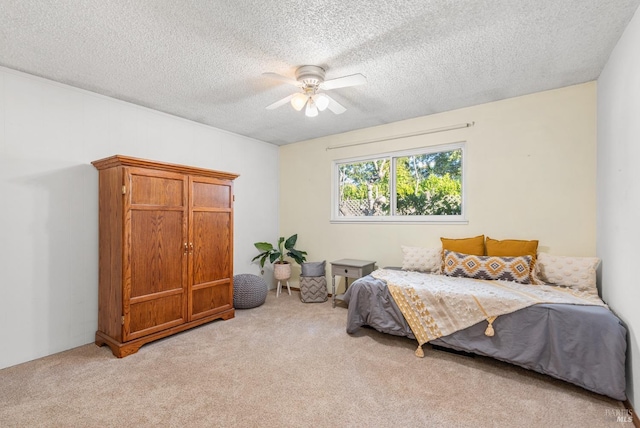 bedroom featuring ceiling fan, light colored carpet, and a textured ceiling