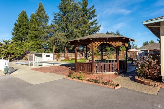 view of property's community with an outdoor structure, a gazebo, a swimming pool, and a patio