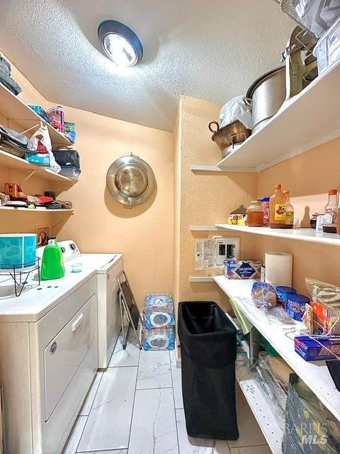 clothes washing area with a textured ceiling and washing machine and clothes dryer