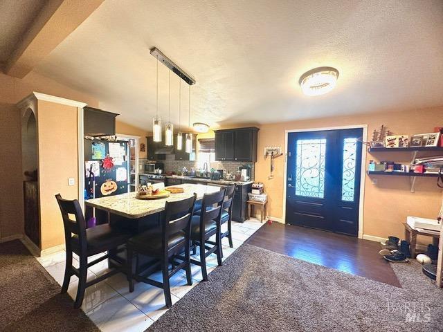 dining area featuring dark hardwood / wood-style flooring, a textured ceiling, sink, and vaulted ceiling