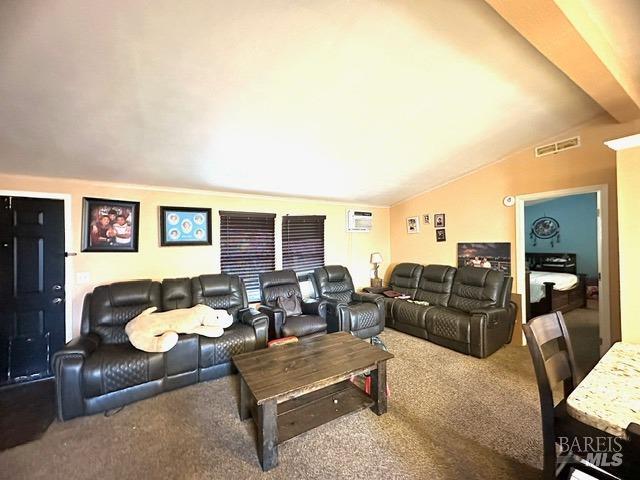 carpeted cinema with an AC wall unit and vaulted ceiling