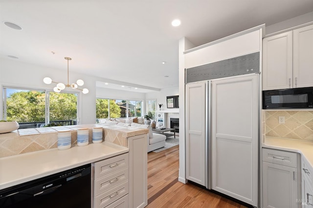 kitchen featuring white cabinets, decorative light fixtures, decorative backsplash, and black appliances