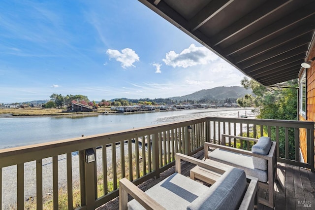 wooden terrace featuring a water and mountain view