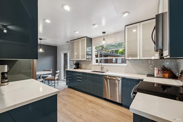 kitchen featuring decorative backsplash, stainless steel appliances, sink, decorative light fixtures, and light hardwood / wood-style floors