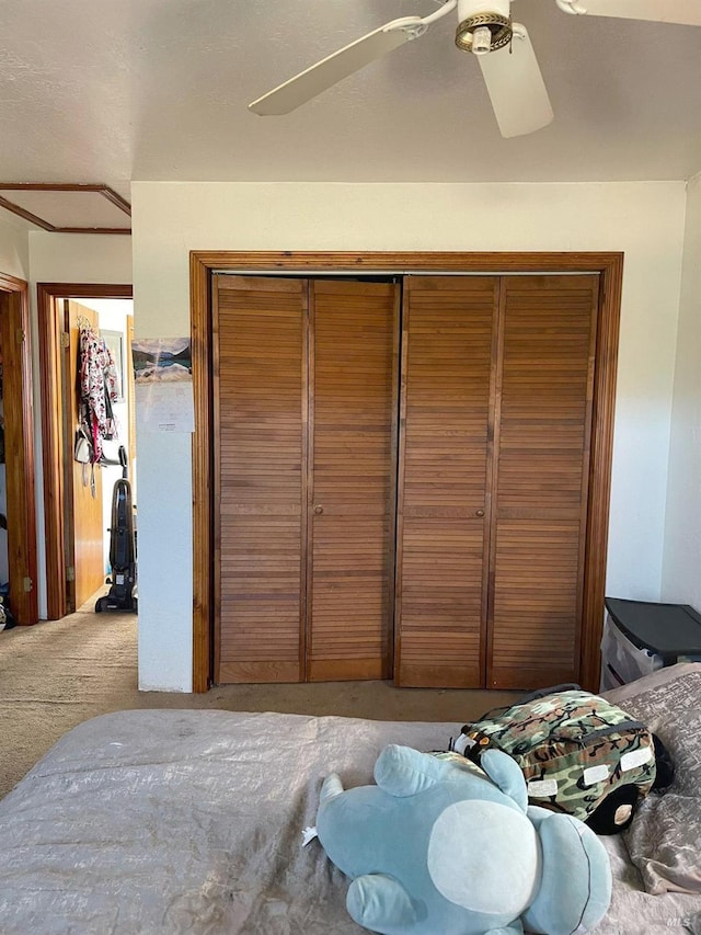 carpeted bedroom featuring ceiling fan and a closet