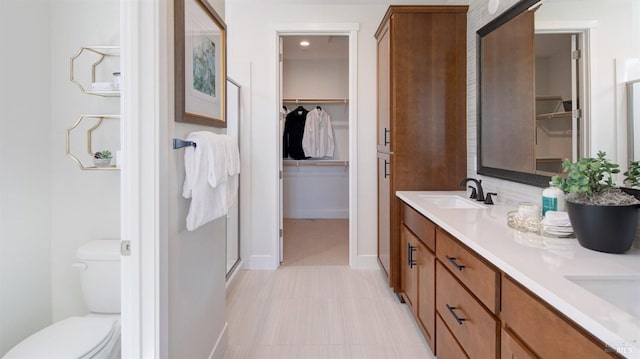 bathroom featuring vanity, a shower with shower door, and toilet