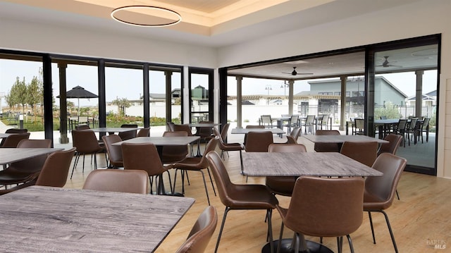 dining space with a wealth of natural light, a water view, and light hardwood / wood-style floors