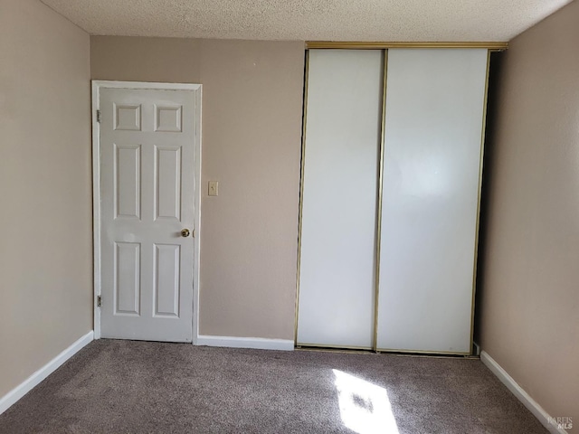 unfurnished bedroom with carpet flooring, a closet, and a textured ceiling