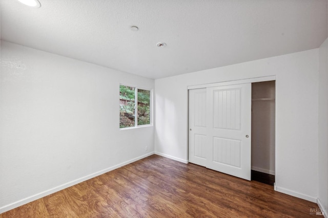 unfurnished bedroom featuring a closet and dark hardwood / wood-style floors