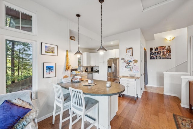 kitchen with kitchen peninsula, stainless steel fridge, a breakfast bar, white cabinets, and dark hardwood / wood-style floors