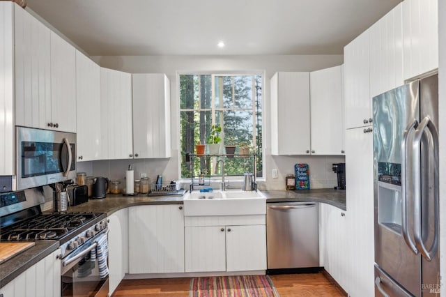 kitchen with sink, white cabinetry, stainless steel appliances, and light wood-type flooring