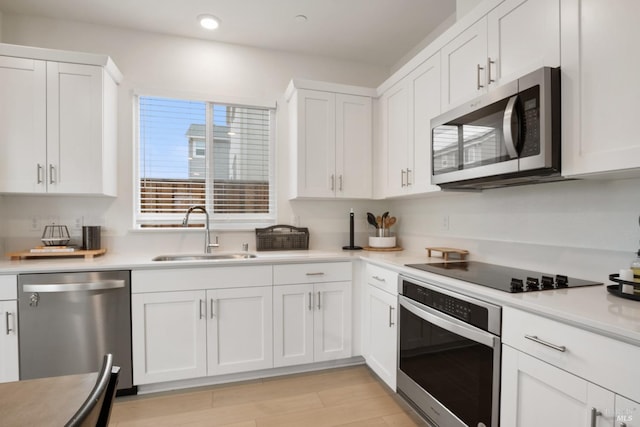 kitchen featuring appliances with stainless steel finishes, sink, white cabinets, and light hardwood / wood-style floors