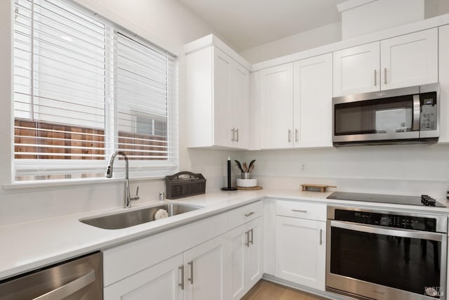 kitchen with stainless steel appliances, white cabinetry, and sink