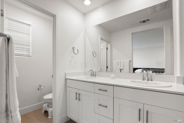 bathroom with vanity, toilet, and hardwood / wood-style floors