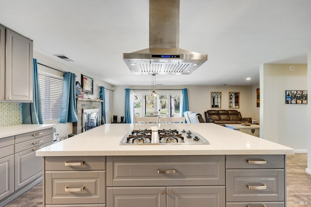 kitchen featuring island exhaust hood, gray cabinets, a kitchen island, and a wealth of natural light
