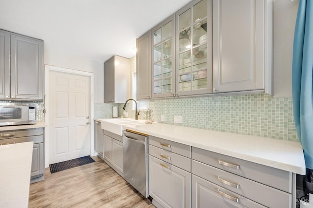 kitchen featuring sink, gray cabinets, appliances with stainless steel finishes, tasteful backsplash, and light hardwood / wood-style floors
