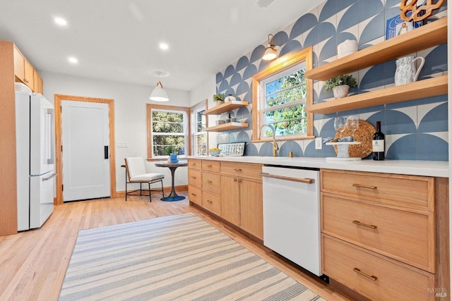 kitchen featuring light wood-type flooring, light brown cabinetry, and white appliances