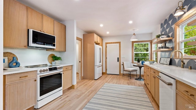 kitchen with light brown cabinets, light hardwood / wood-style floors, white appliances, and sink