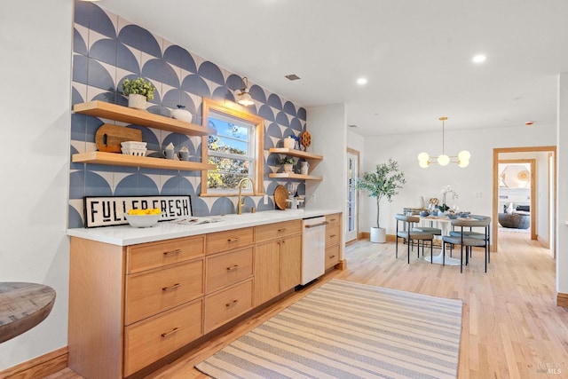 kitchen with light wood-type flooring, white dishwasher, light brown cabinets, an inviting chandelier, and hanging light fixtures