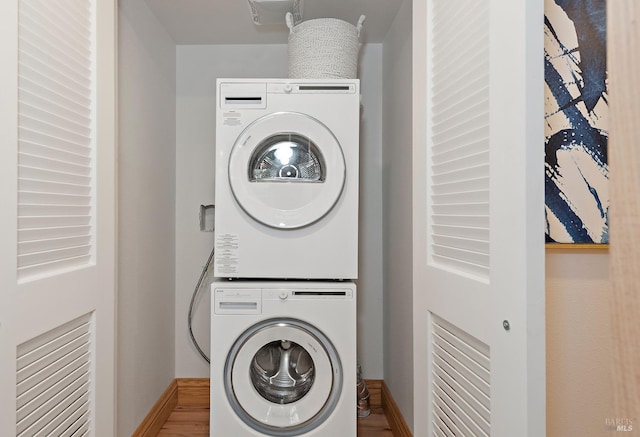 laundry room featuring stacked washer and dryer and hardwood / wood-style flooring