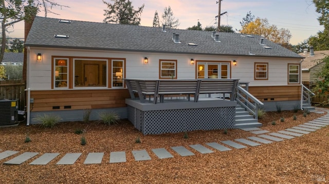 back house at dusk featuring central AC and a wooden deck