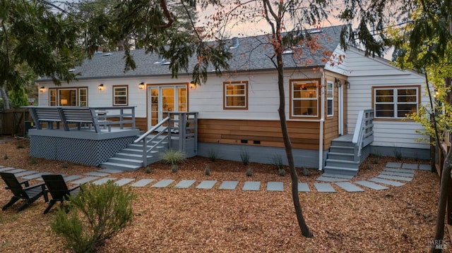 back house at dusk featuring a wooden deck