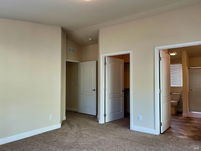 unfurnished bedroom featuring carpet, ensuite bath, and lofted ceiling