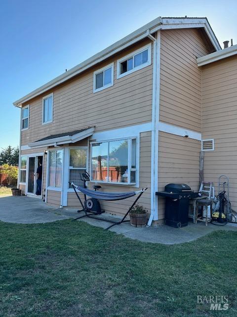 back of property with a lawn and a patio area