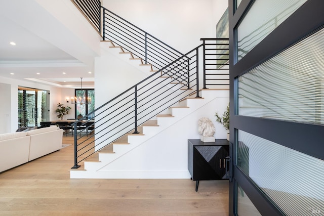 stairway with hardwood / wood-style floors and a notable chandelier