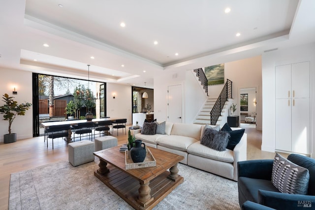 living room featuring a tray ceiling and light hardwood / wood-style flooring