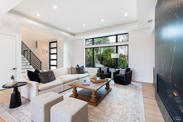 living room featuring a raised ceiling and light hardwood / wood-style flooring