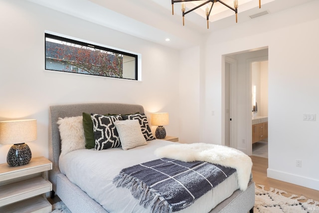 bedroom with ensuite bathroom and hardwood / wood-style floors